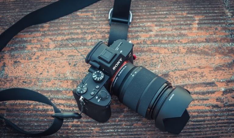 木製テーブルの上に置かれたSonyのミラーレスカメラとズームレンズ