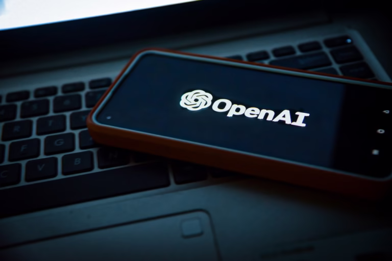 スマートフォンに表示されたOpenAIロゴとノートパソコン。ChatGPTやAI活用を解説する記事用イメージ