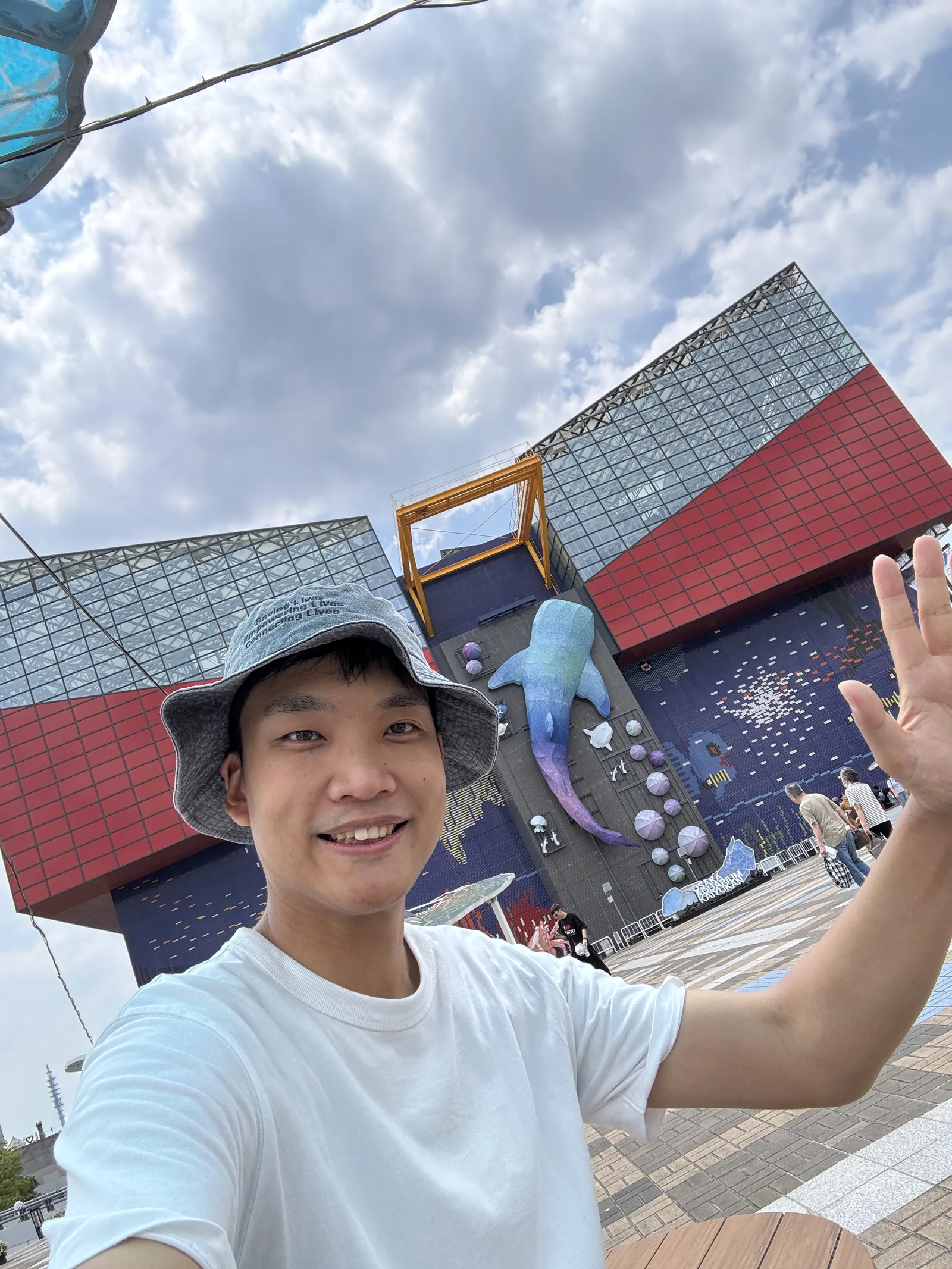 海遊館の建物を背景に手を振るどう旅の講師